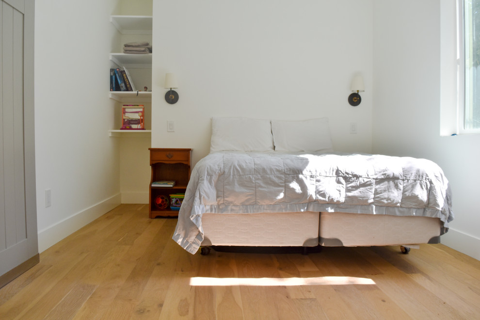 Foto de dormitorio tipo loft tradicional de tamaño medio con paredes blancas, suelo laminado y suelo marrón