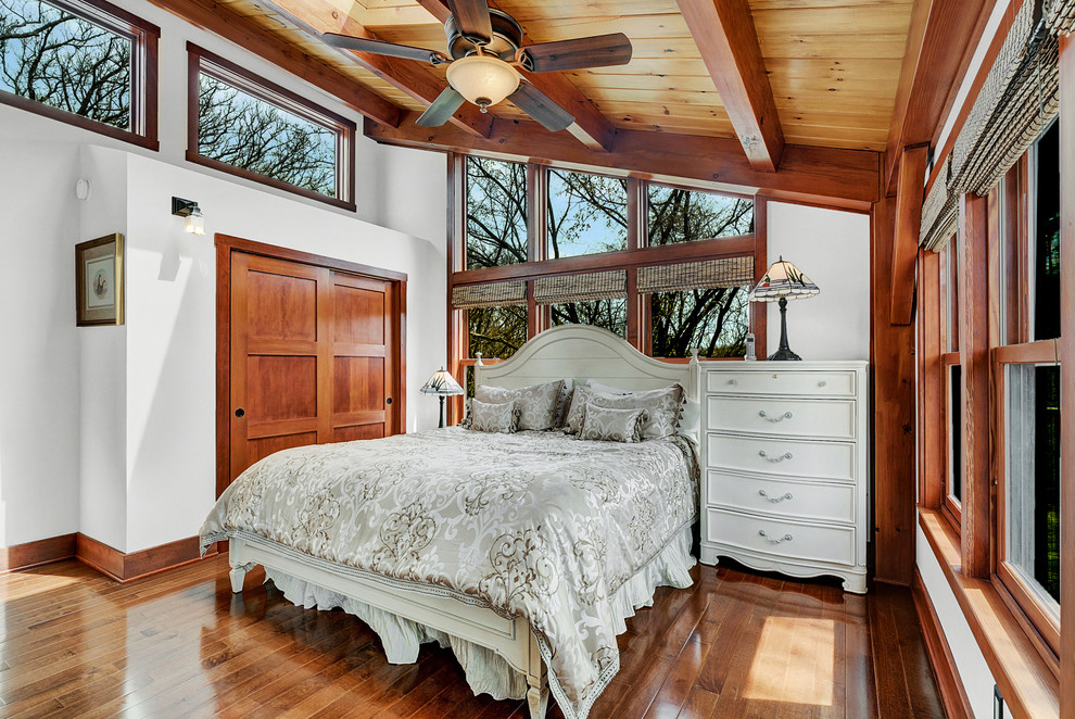 Cette image montre une chambre parentale craftsman de taille moyenne avec un sol en bois brun et un sol marron.