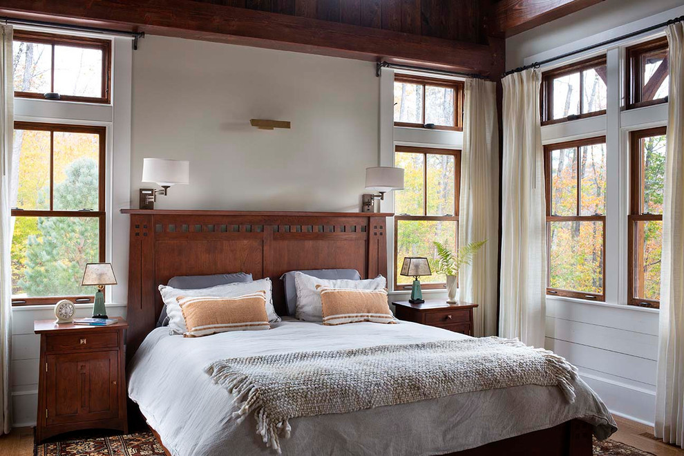 Idée de décoration pour une chambre parentale chalet de taille moyenne avec un mur blanc, un sol en bois brun et un sol marron.