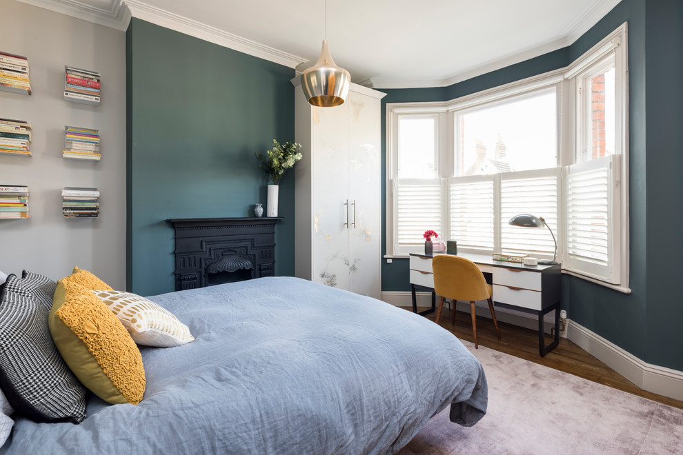 ロンドンにあるトランジショナルスタイルのおしゃれな寝室 (緑の壁、無垢フローリング、標準型暖炉、茶色い床) のレイアウト