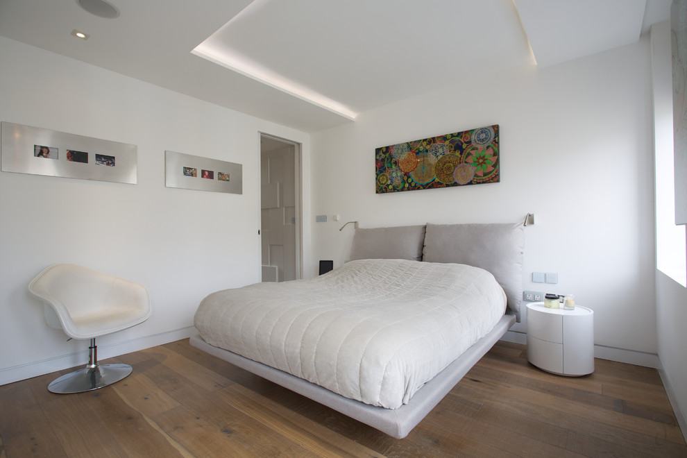 Immagine di una camera da letto contemporanea con pareti bianche e pavimento in legno massello medio