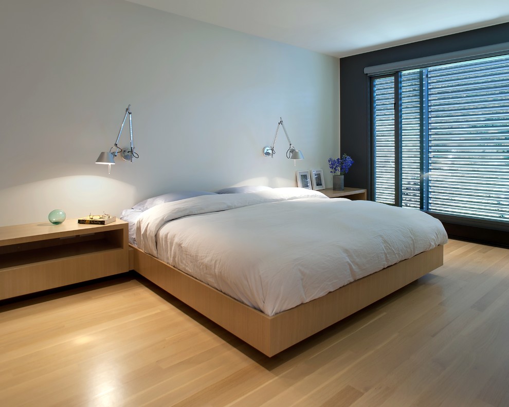 Пример оригинального дизайна: спальня в стиле модернизм с белыми стенами и светлым паркетным полом