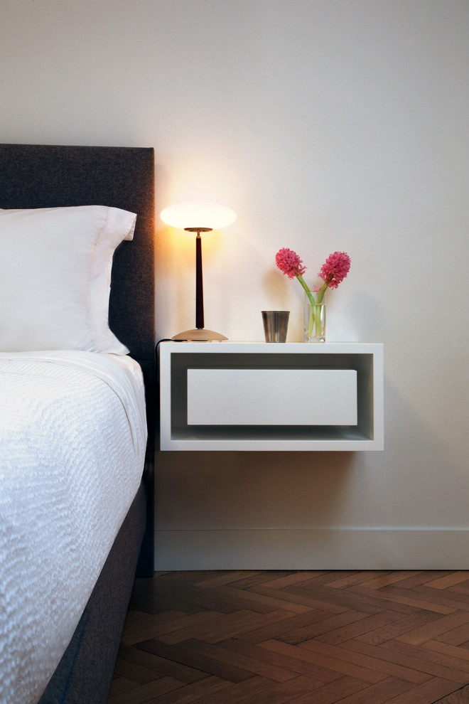 Small minimalist master medium tone wood floor bedroom photo in New York with white walls