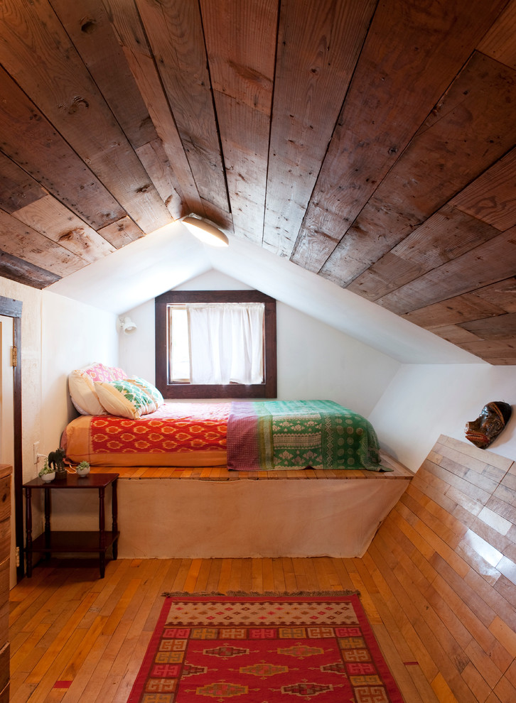 Exemple d'une petite chambre mansardée ou avec mezzanine éclectique avec un mur blanc, un sol en bois brun et aucune cheminée.