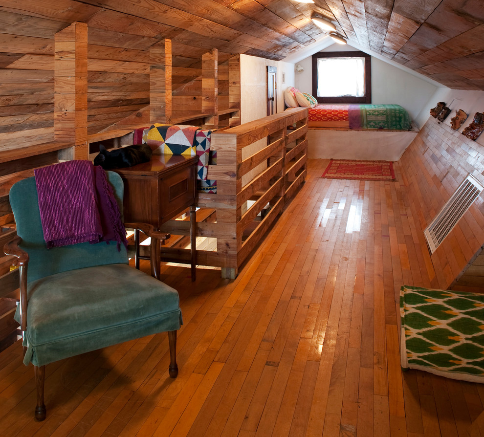 Photo of a small bohemian mezzanine loft bedroom in Austin with multi-coloured walls, medium hardwood flooring and no fireplace.