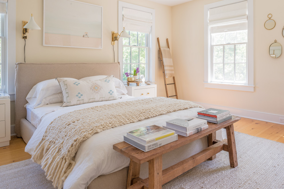 Diseño de dormitorio marinero sin chimenea con paredes beige y suelo de madera clara