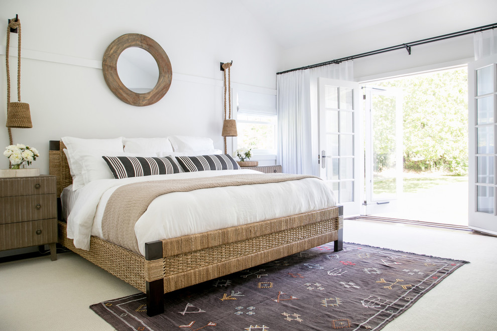 This is an example of an expansive coastal master bedroom in New York with white walls and medium hardwood flooring.