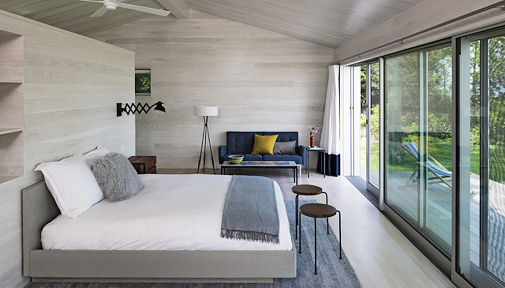 Imagen de dormitorio principal costero de tamaño medio sin chimenea con paredes beige, suelo de madera clara y suelo beige