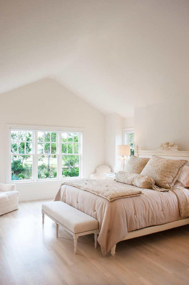 Coastal bedroom in New York with white walls and medium hardwood flooring.