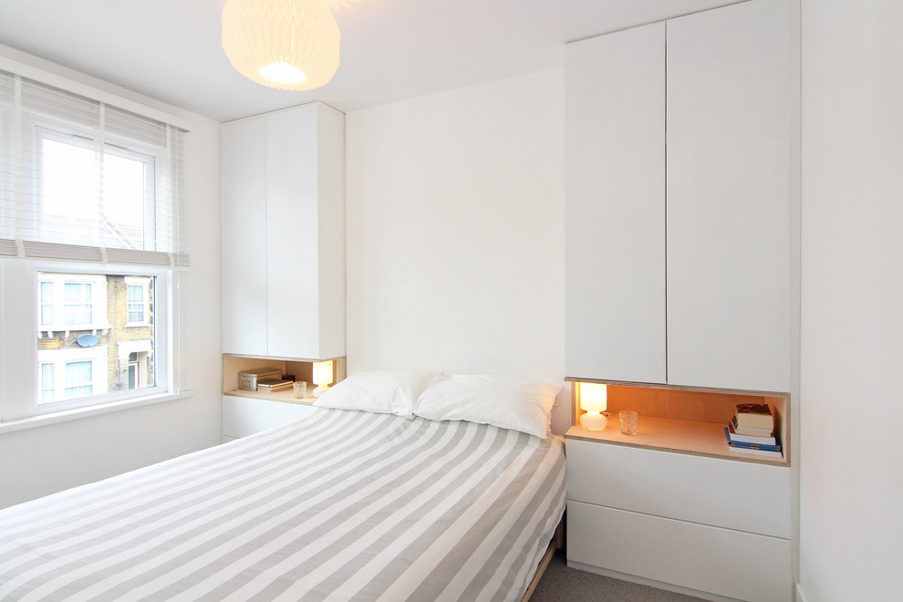 This is an example of a medium sized contemporary bedroom in London with white walls, carpet and grey floors.