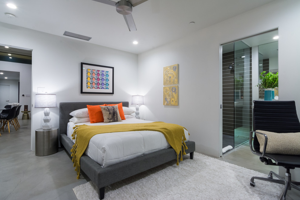 Immagine di una camera da letto design con pareti bianche e pavimento in cemento