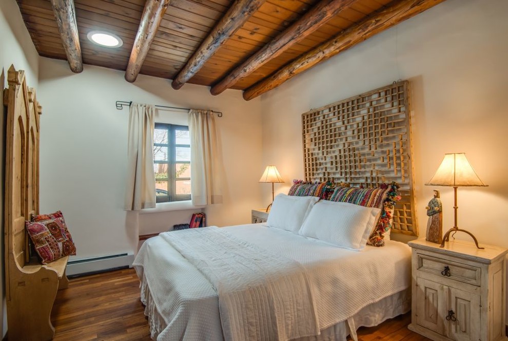 Idée de décoration pour une petite chambre parentale sud-ouest américain avec un mur beige, un sol en bois brun, aucune cheminée et un sol marron.