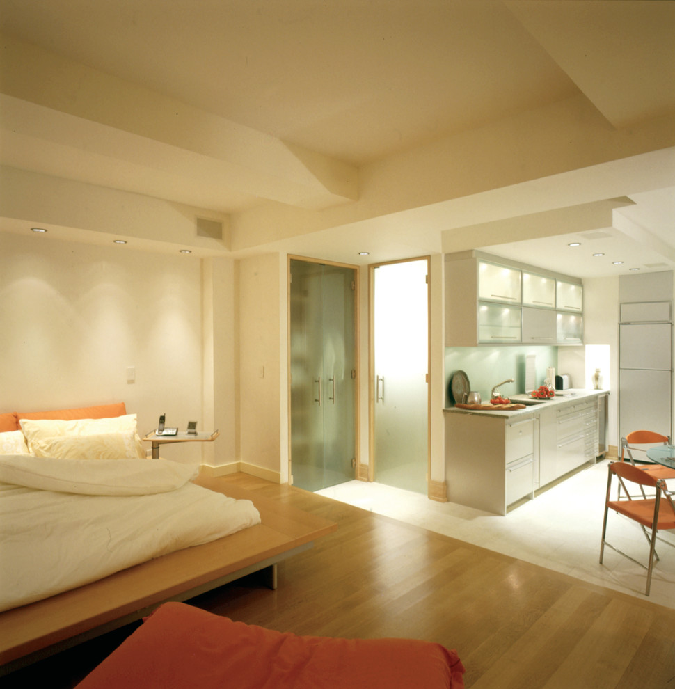 Imagen de dormitorio tipo loft moderno de tamaño medio con paredes blancas y suelo de madera clara