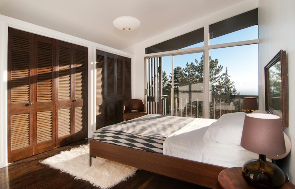 Ejemplo de dormitorio actual con paredes blancas y suelo de madera oscura