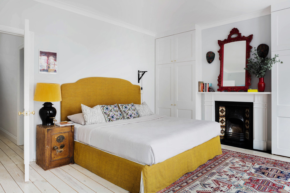 Stilmix Hauptschlafzimmer mit grauer Wandfarbe, hellem Holzboden und Kamin in London