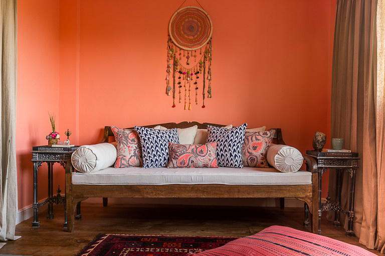 Exemple d'une grande chambre parentale éclectique avec un mur orange et un sol en bois brun.