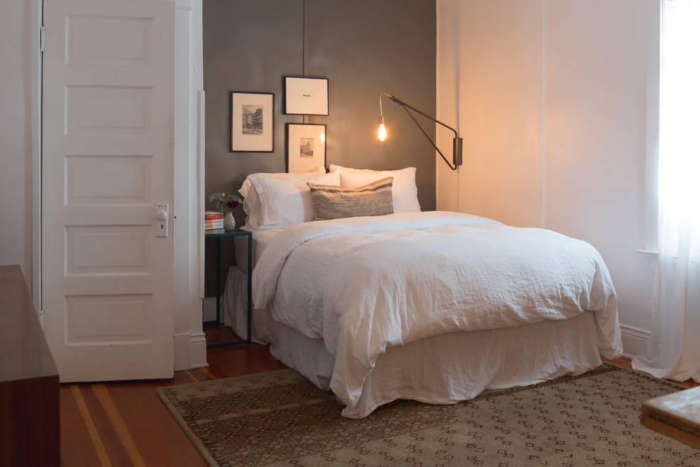 Diseño de dormitorio principal ecléctico pequeño sin chimenea con paredes grises, suelo de madera en tonos medios y suelo marrón