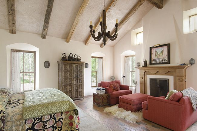 Large bohemian master bedroom in Albuquerque with white walls, brick flooring, a standard fireplace and a wooden fireplace surround.