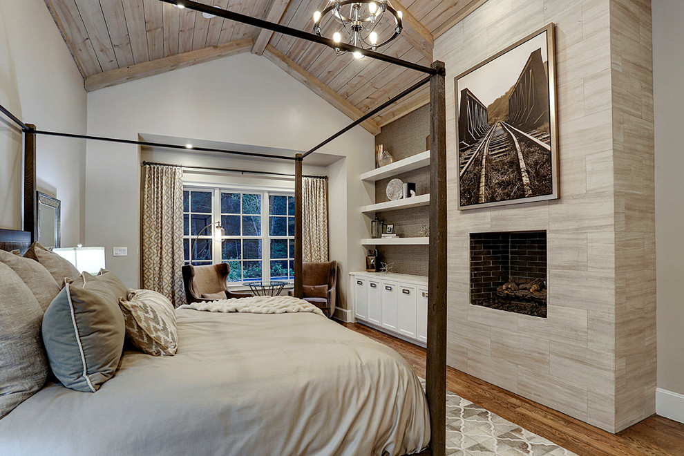 Großes Country Hauptschlafzimmer mit beiger Wandfarbe, braunem Holzboden, Kamin, gefliester Kaminumrandung und braunem Boden in Houston