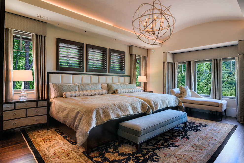 Diseño de dormitorio principal bohemio grande con paredes beige, suelo de madera en tonos medios, chimenea lineal y marco de chimenea de piedra