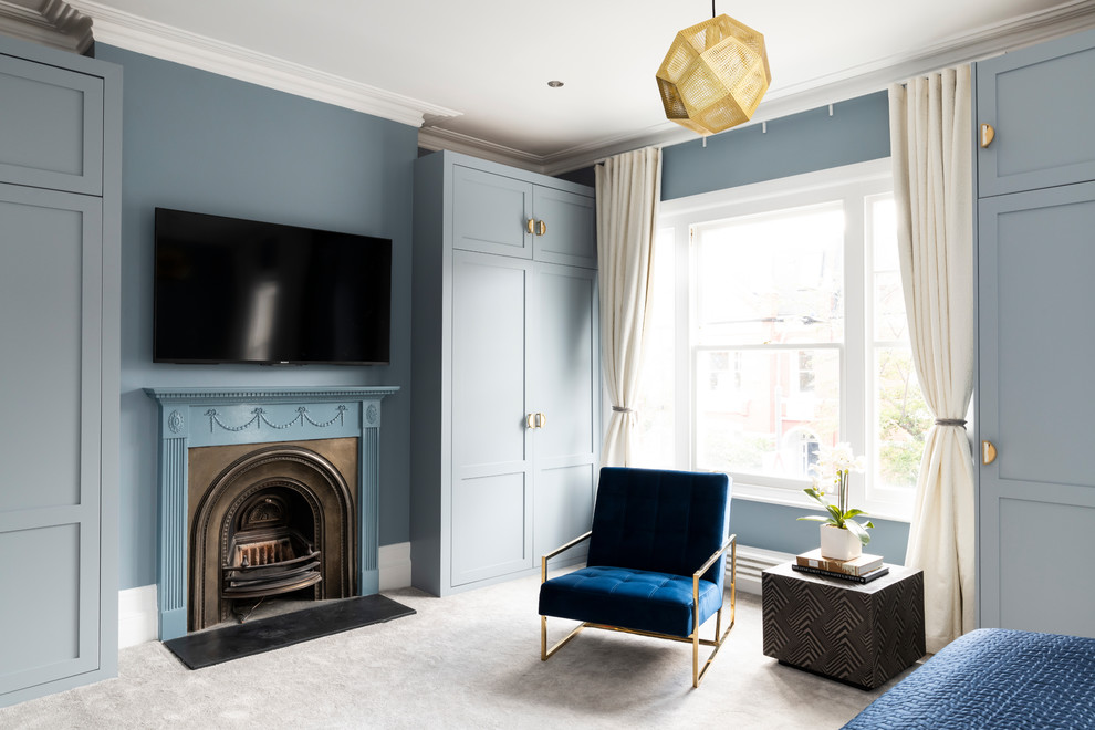 Modernes Hauptschlafzimmer mit blauer Wandfarbe, Teppichboden, Kamin, Kaminumrandung aus Metall und grauem Boden in London