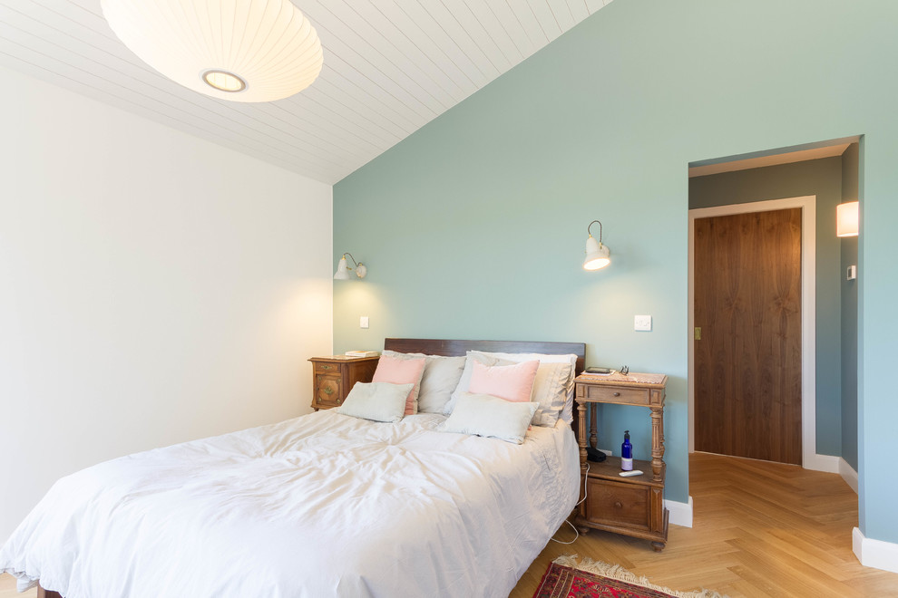 Mittelgroßes Skandinavisches Schlafzimmer mit blauer Wandfarbe, hellem Holzboden und beigem Boden in London