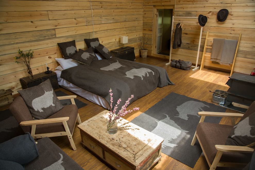 Cette photo montre une chambre parentale montagne de taille moyenne avec un sol en bois brun et un poêle à bois.