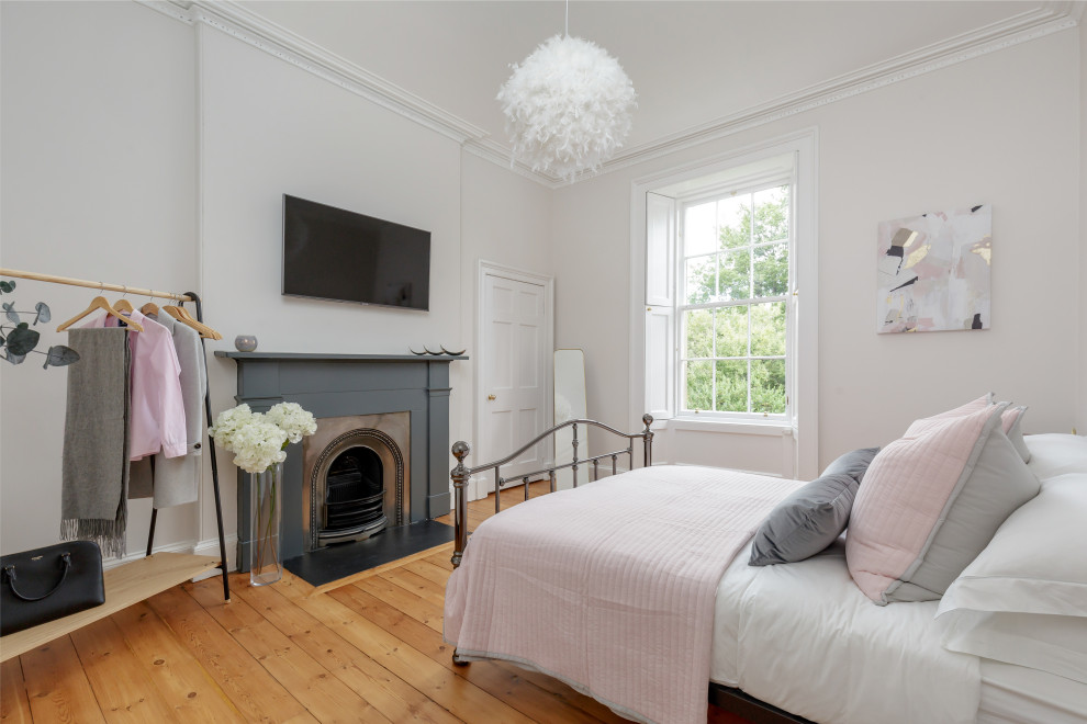 Traditional grey and pink bedroom in Other with grey walls, medium hardwood flooring, a standard fireplace, brown floors and a chimney breast.