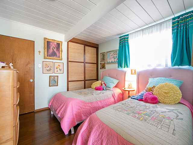 Bild på ett mellanstort 60 tals sovrum, med vita väggar och mellanmörkt trägolv