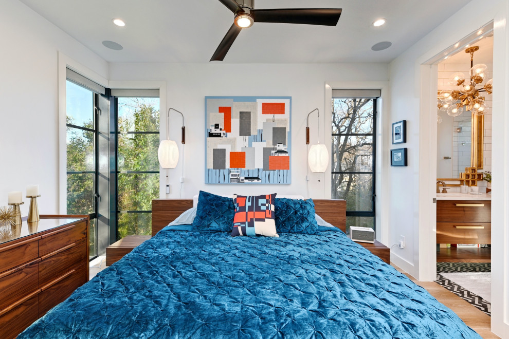Trendy medium tone wood floor and brown floor bedroom photo in Austin with white walls