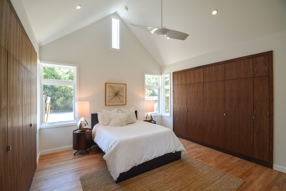 This is an example of a large contemporary master bedroom in Austin with white walls, medium hardwood flooring, no fireplace and brown floors.