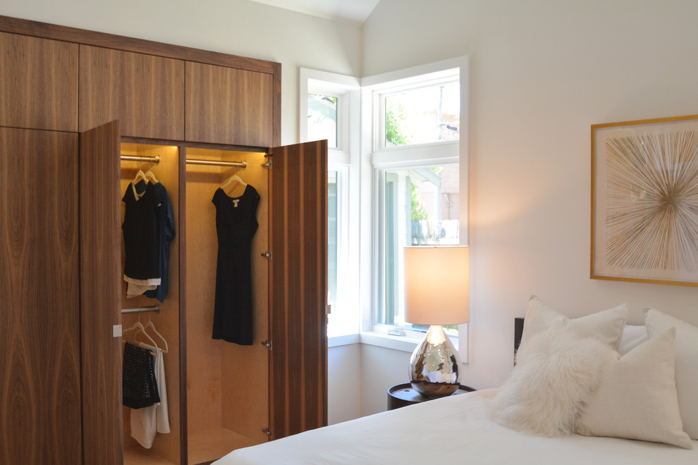 Modelo de dormitorio principal actual grande sin chimenea con paredes blancas, suelo de madera en tonos medios y suelo marrón