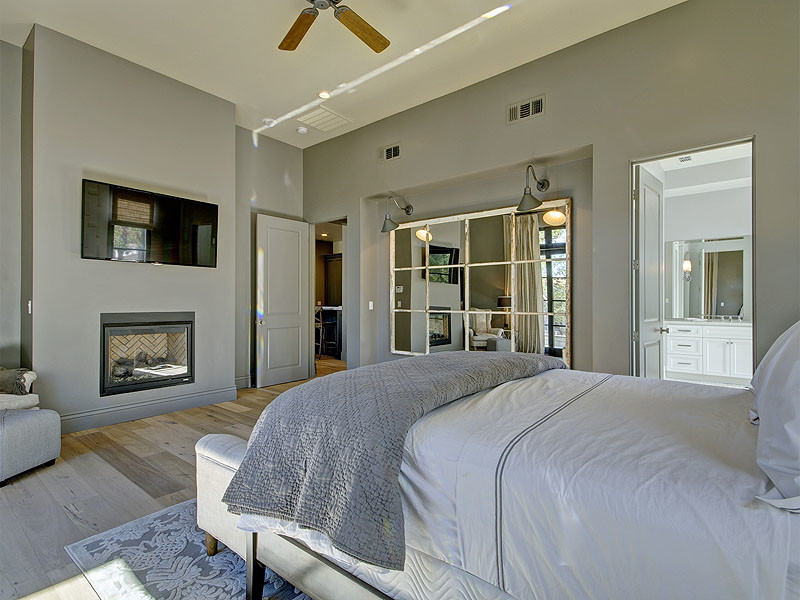 Großes Modernes Hauptschlafzimmer mit grauer Wandfarbe, hellem Holzboden, Kamin, Kaminumrandung aus Metall und beigem Boden in Sacramento