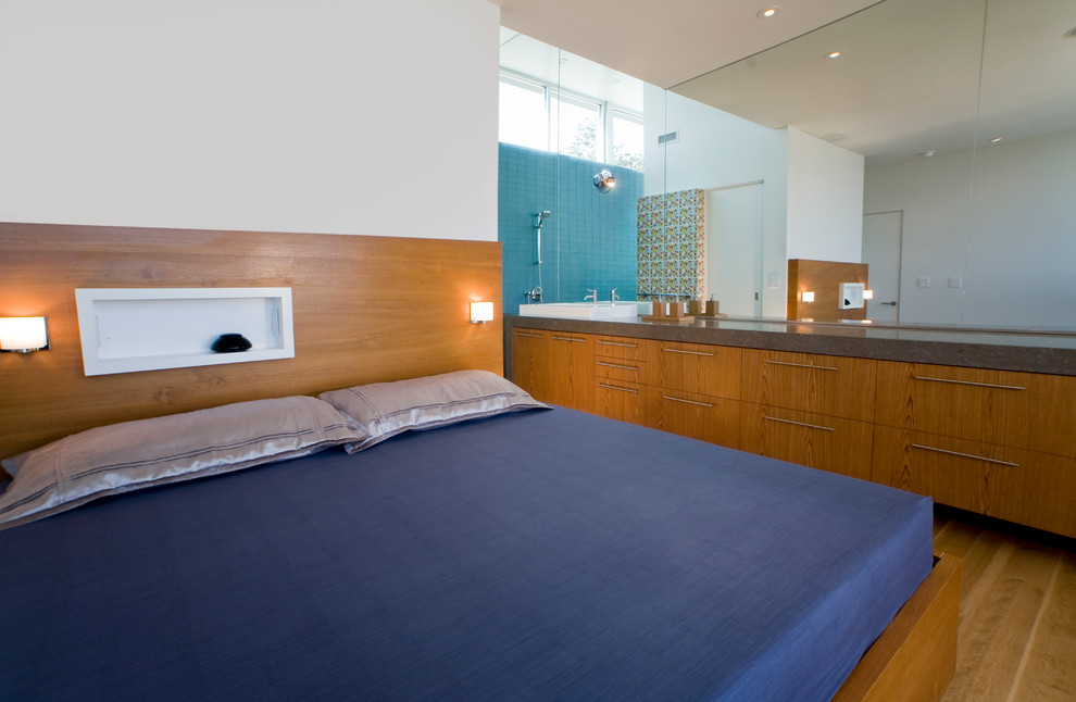 Esempio di una camera da letto design con pareti bianche, pavimento in legno massello medio e nessun camino
