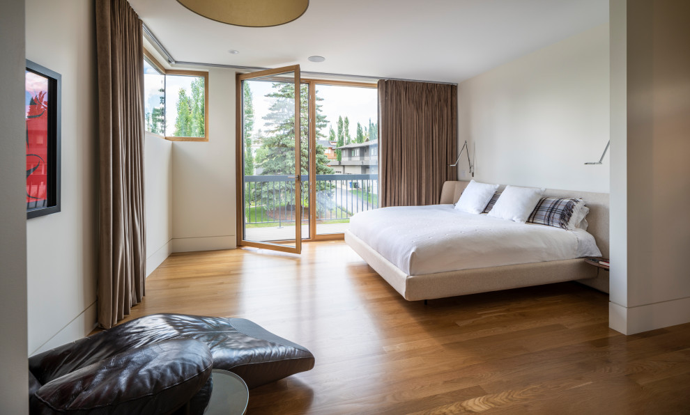 Modernes Schlafzimmer mit weißer Wandfarbe, braunem Holzboden und braunem Boden in Calgary