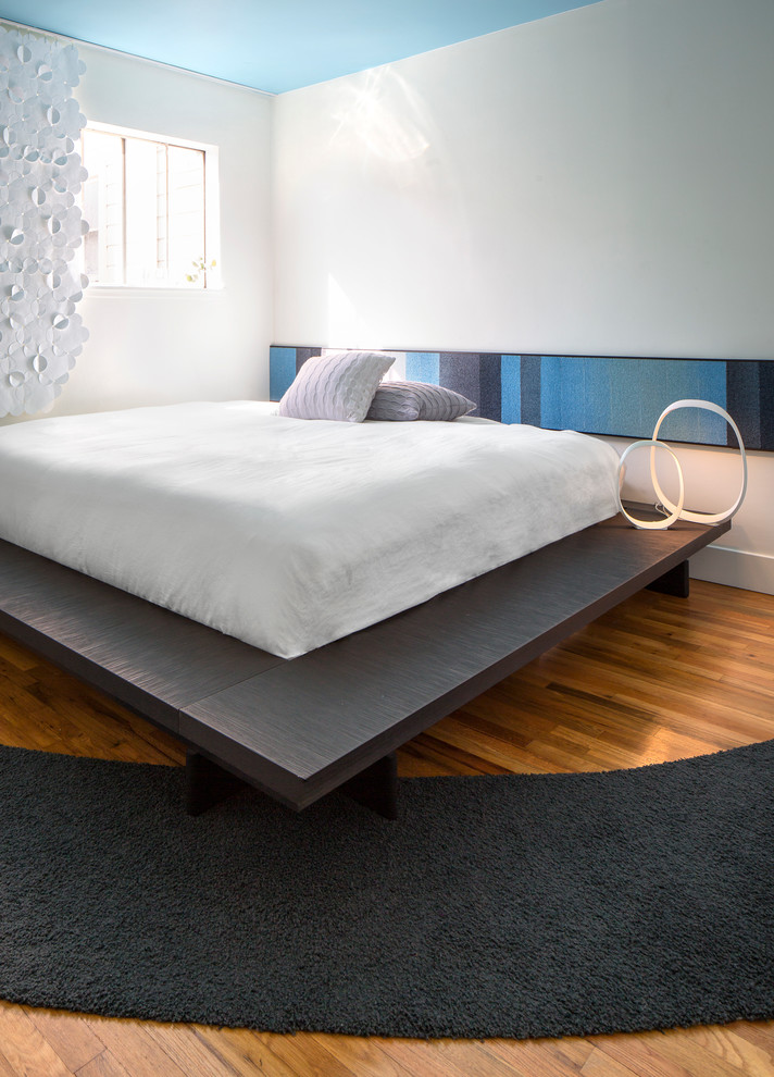 Example of a small minimalist master medium tone wood floor bedroom design in Los Angeles with white walls