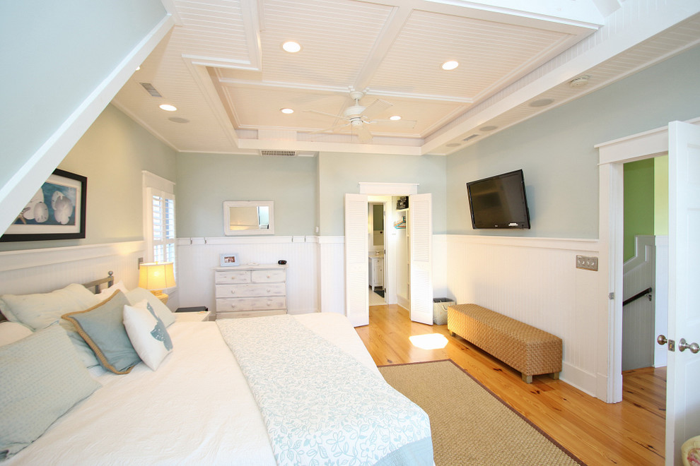 Modelo de dormitorio principal marinero grande sin chimenea con paredes azules, suelo de madera en tonos medios y suelo marrón