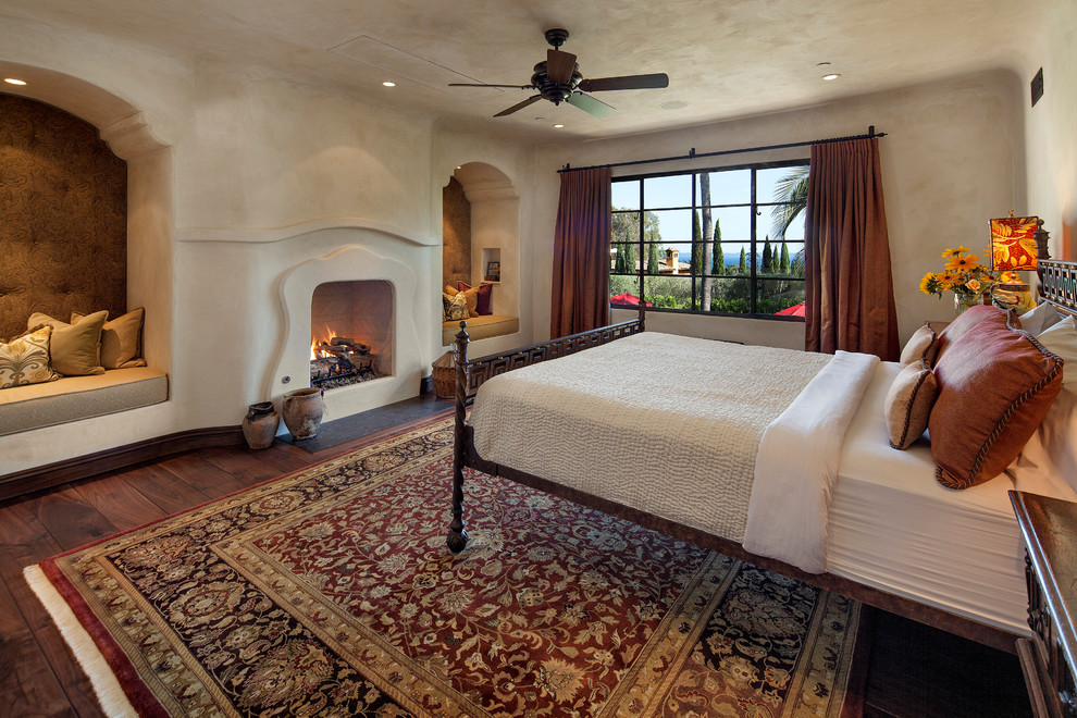 サンタバーバラにある広い地中海スタイルのおしゃれな主寝室 (ベージュの壁、標準型暖炉、無垢フローリング) のレイアウト