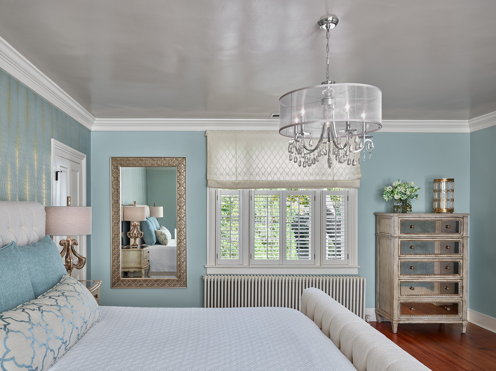 Aménagement d'une chambre parentale classique de taille moyenne avec un mur bleu, un sol en bois brun, une cheminée standard, un sol marron et un manteau de cheminée en pierre.