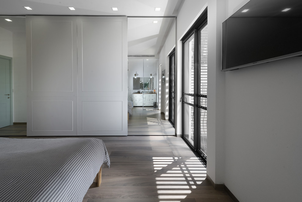 Imagen de habitación de invitados contemporánea grande sin chimenea con paredes blancas y suelo de contrachapado