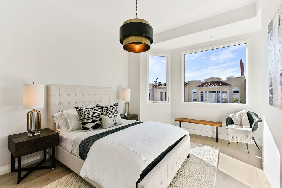 Ejemplo de habitación de invitados contemporánea de tamaño medio sin chimenea con suelo de madera clara y paredes blancas