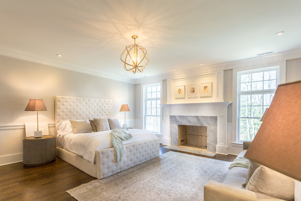 This is an example of a large classic master bedroom in New York with beige walls, medium hardwood flooring, a standard fireplace and a stone fireplace surround.