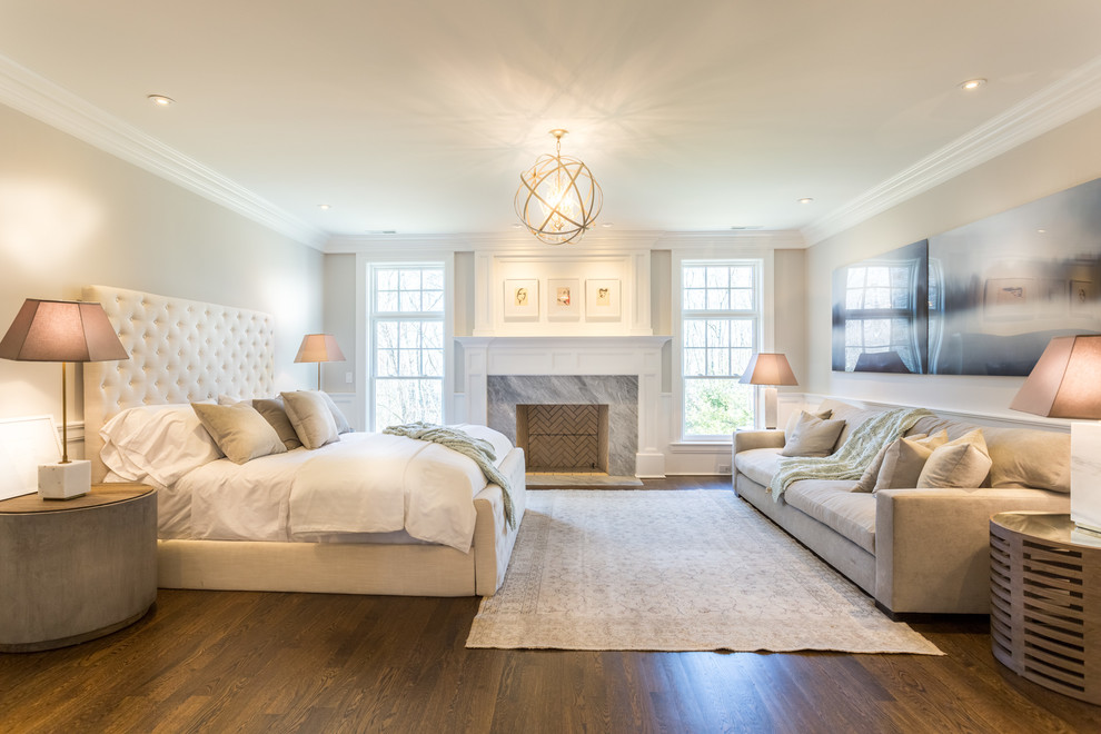 Large transitional master medium tone wood floor bedroom photo in New York with beige walls, a standard fireplace and a stone fireplace