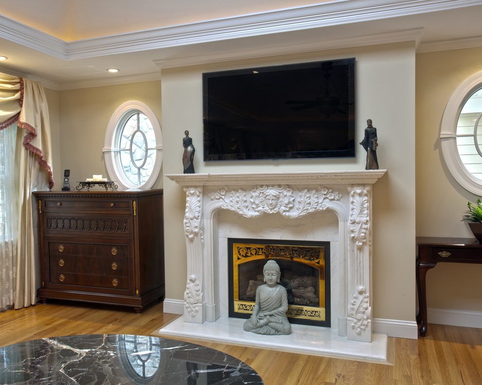 Aménagement d'une chambre parentale classique de taille moyenne avec un mur beige, parquet clair, une cheminée standard et un manteau de cheminée en pierre.