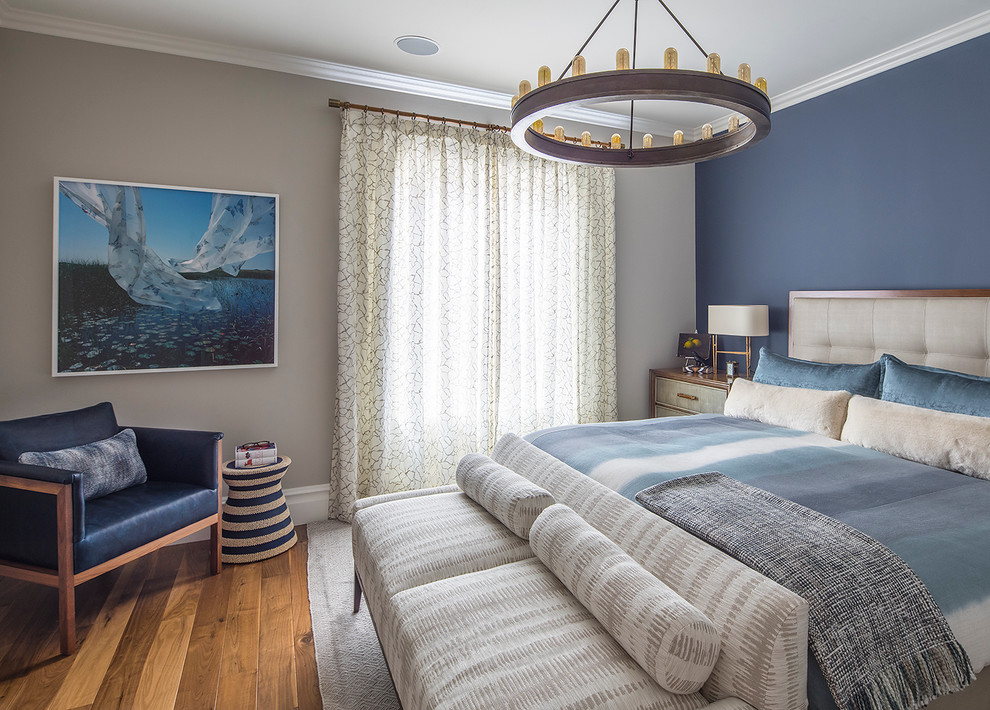Aménagement d'une chambre parentale bord de mer avec un mur bleu et un sol en bois brun.