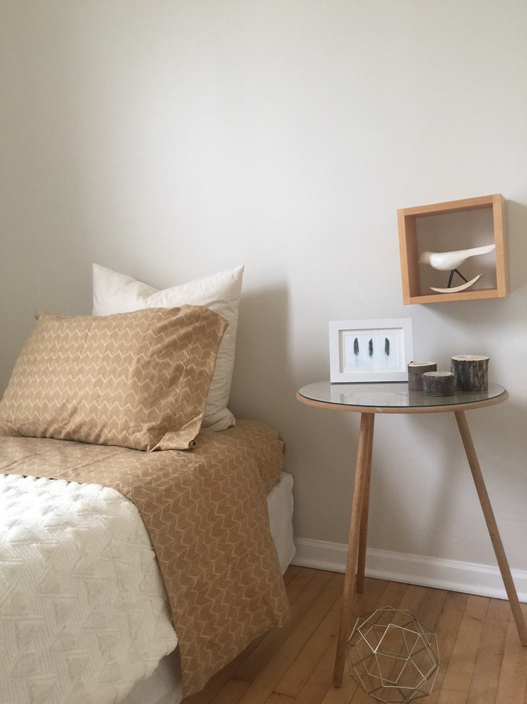 Modelo de habitación de invitados escandinava pequeña sin chimenea con paredes grises, suelo de madera en tonos medios y suelo beige