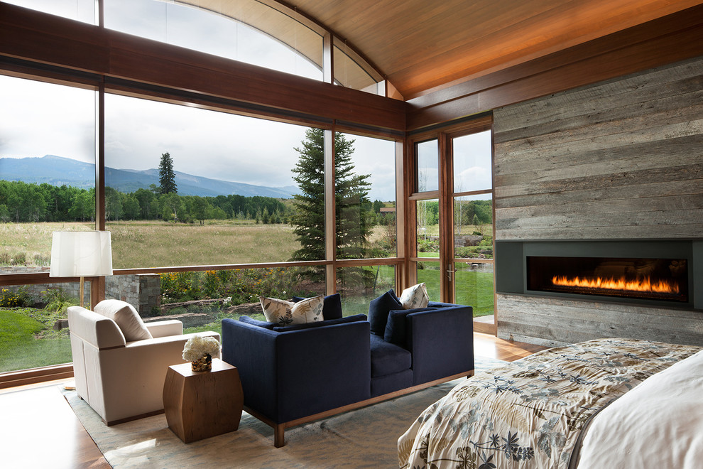 Photo of an expansive rustic master bedroom in Denver with a ribbon fireplace and a metal fireplace surround.