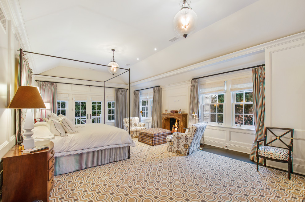 На фото: огромная хозяйская спальня в классическом стиле с белыми стенами, темным паркетным полом и стандартным камином с