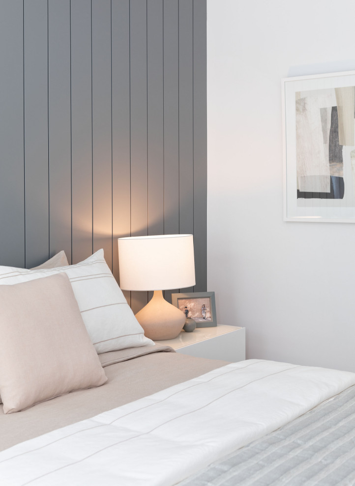 Modelo de habitación de invitados nórdica de tamaño medio con paredes azules, suelo laminado, suelo gris y machihembrado