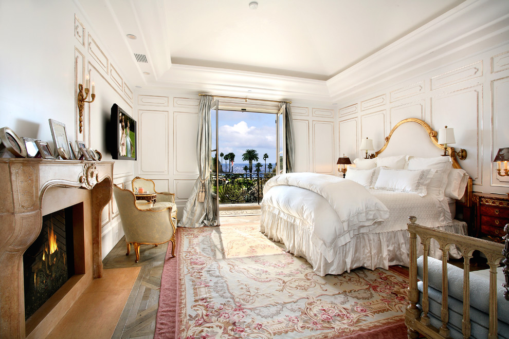 Immagine di una camera da letto mediterranea con pareti bianche, camino classico e TV